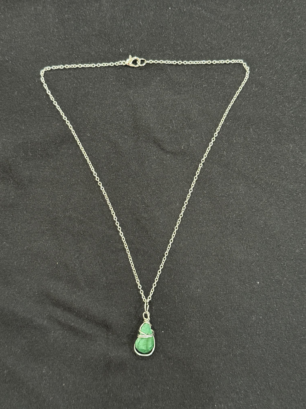 Full view of wrapped emerald stone pendant necklace with 22-inch silver chain