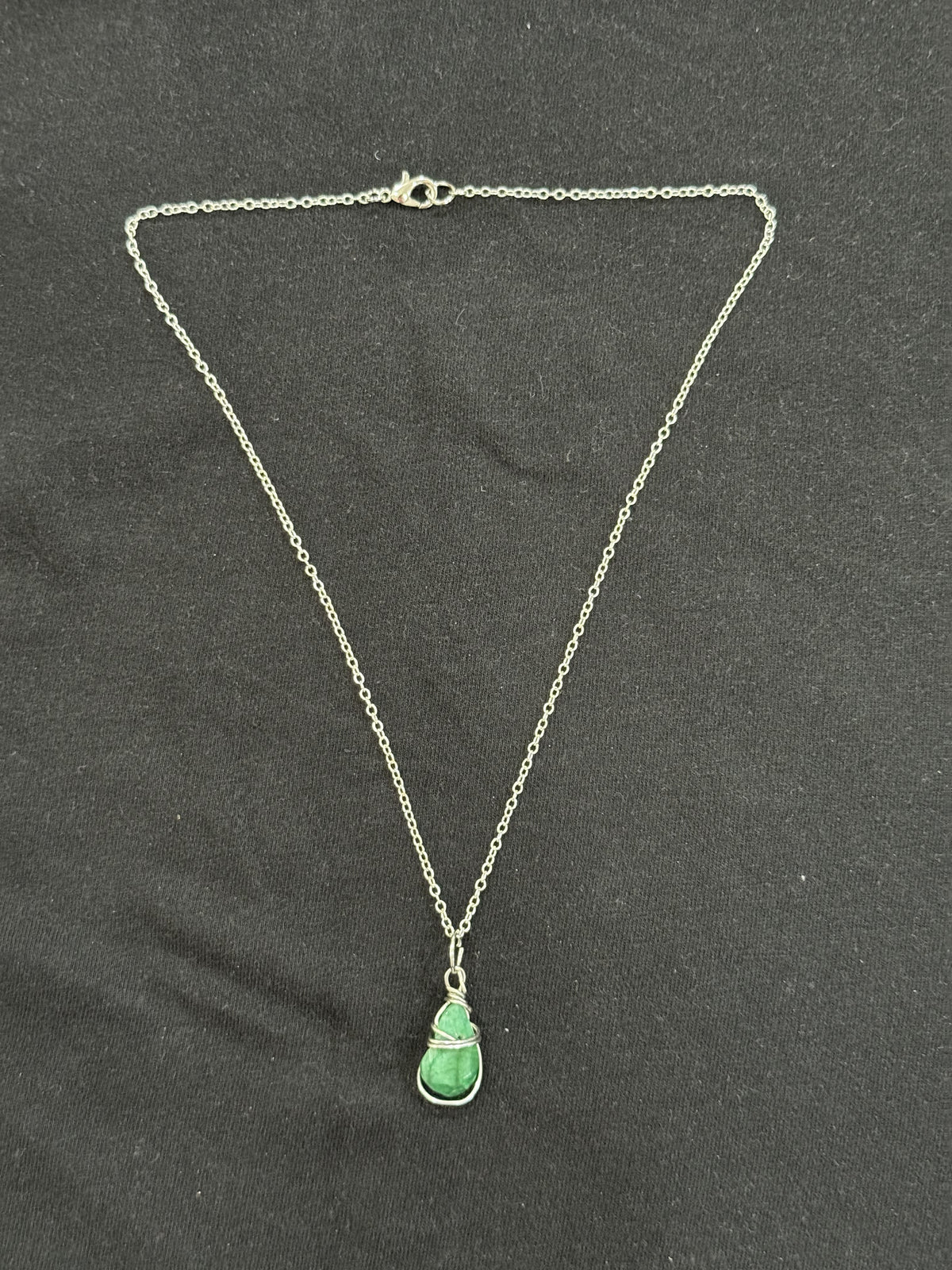 Full view of wrapped emerald stone pendant necklace with 22-inch silver chain