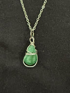 Close-up of green teardrop-shaped emerald stone with decorative wire wrapping