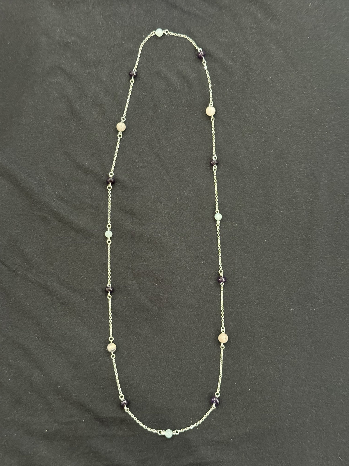 Full view of long silver-tone chain necklace with spaced aquamarine, amethyst and porcelain jasper stones