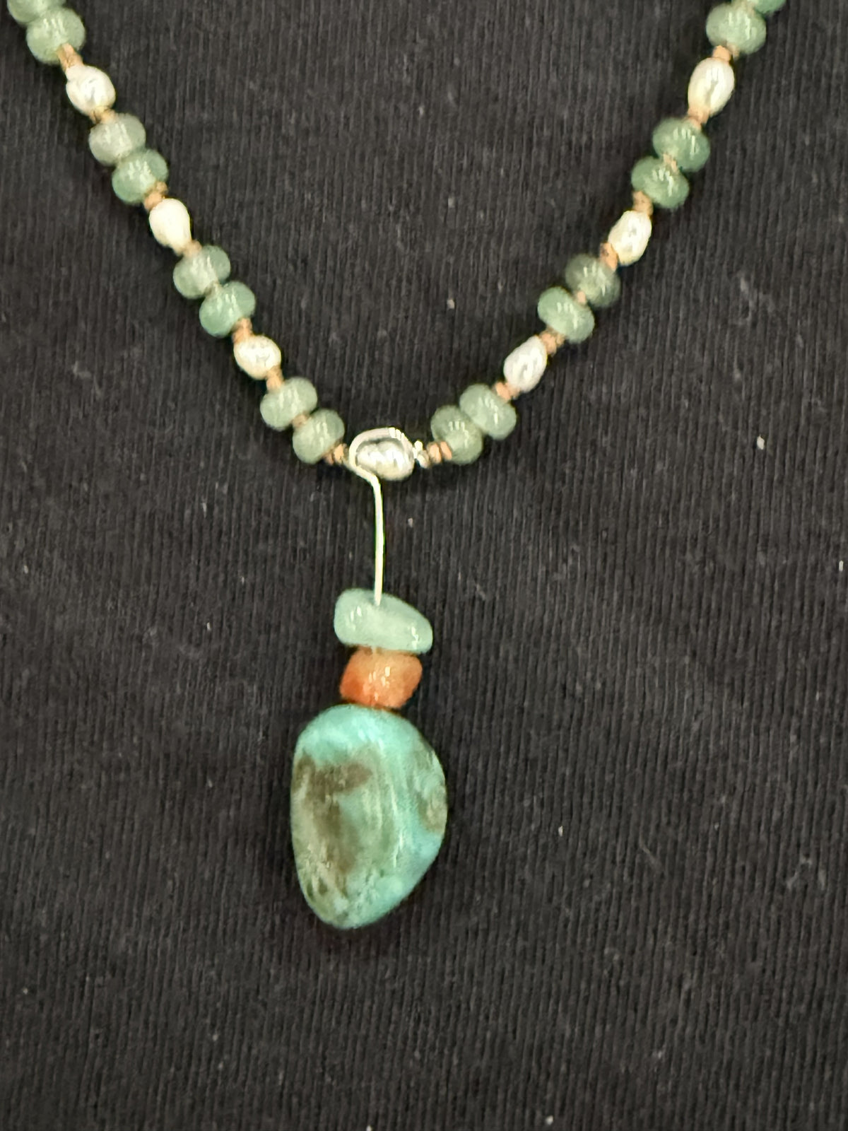 Close-up of turquoise pendant with aventurine and red carnelian accents