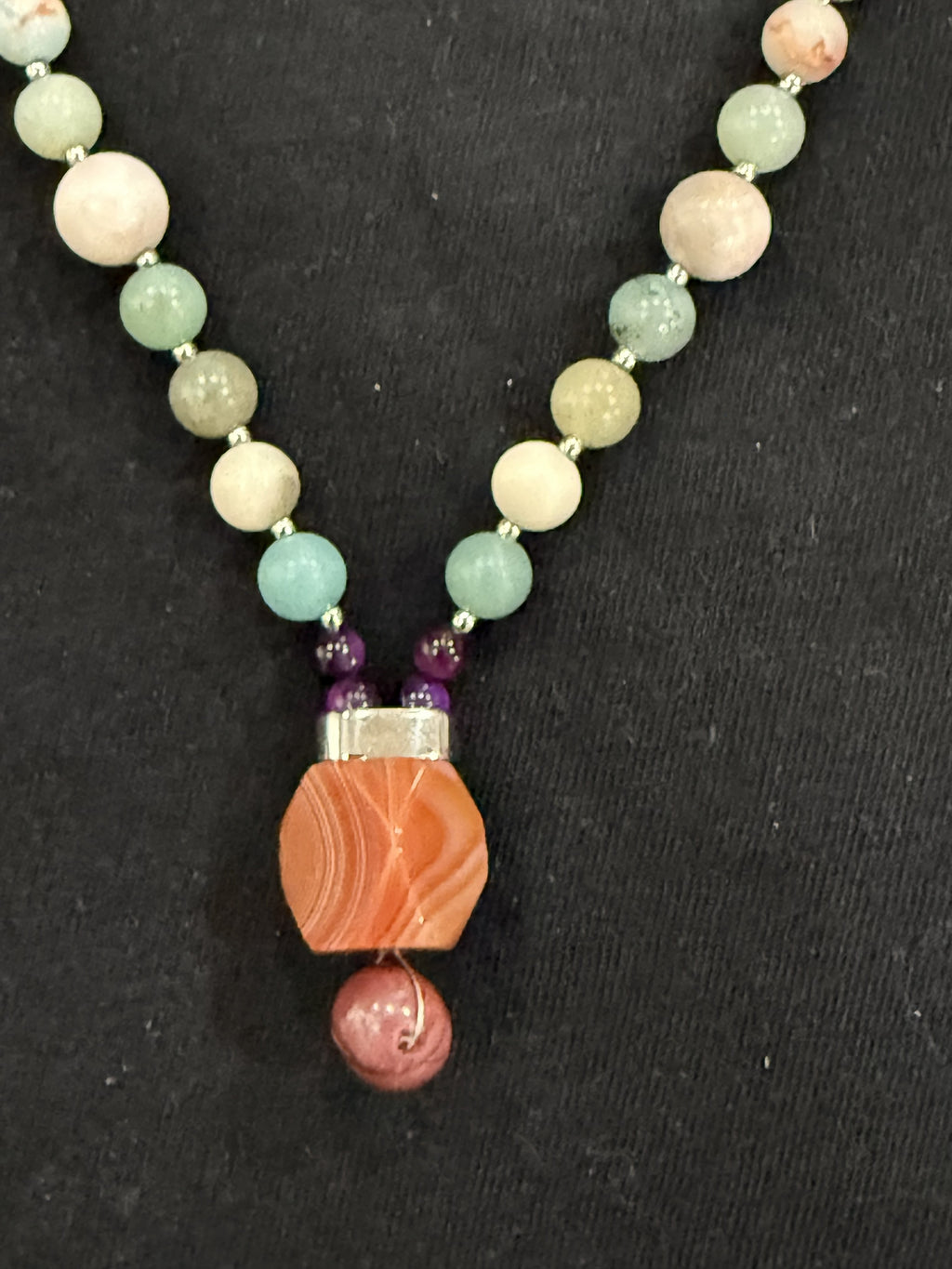 Close-up of red carnelian and mookaite pendant with purple tiger’s eye bead accents