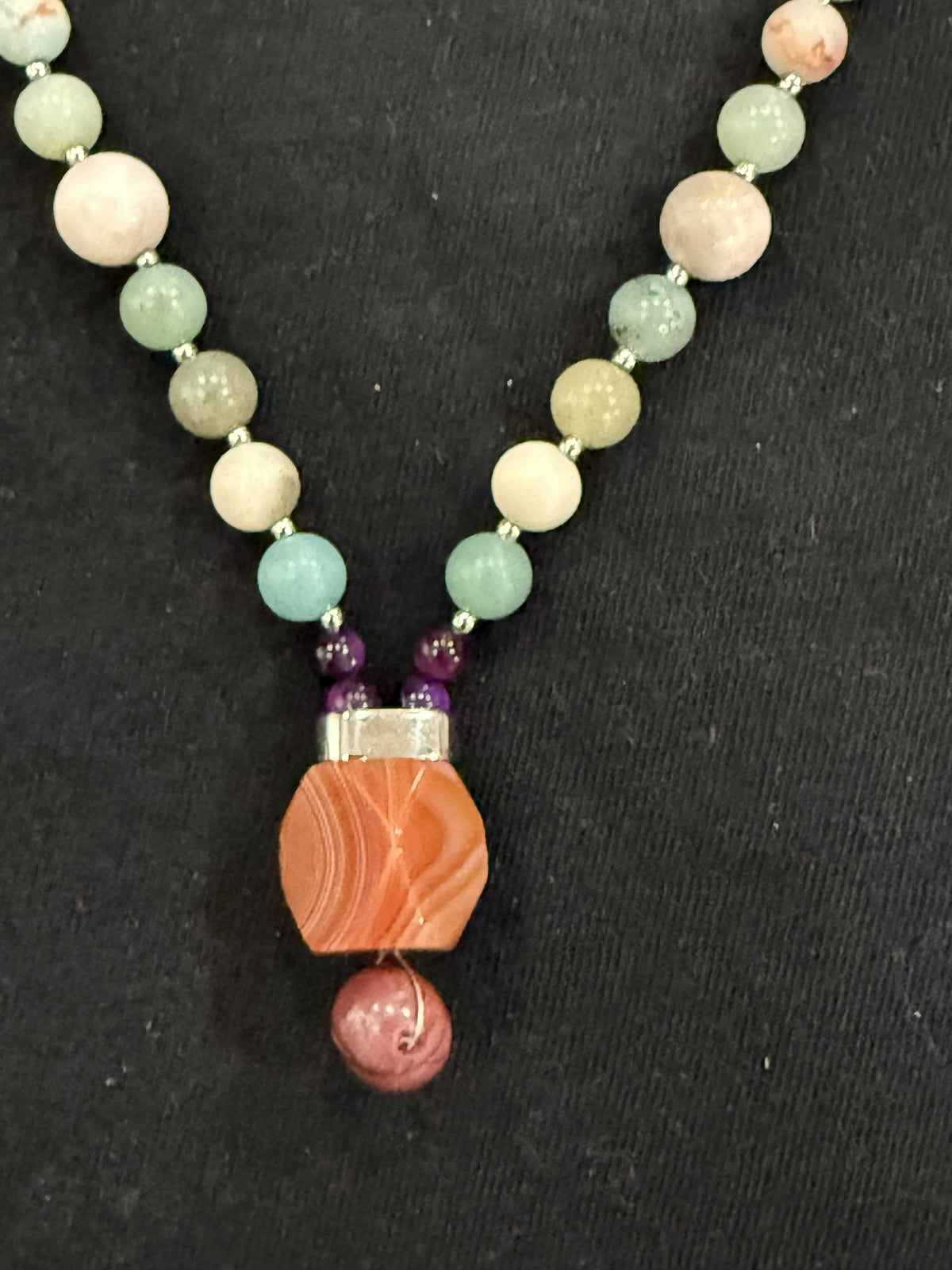 Close-up of red carnelian and mookaite pendant with purple tiger’s eye bead accents
