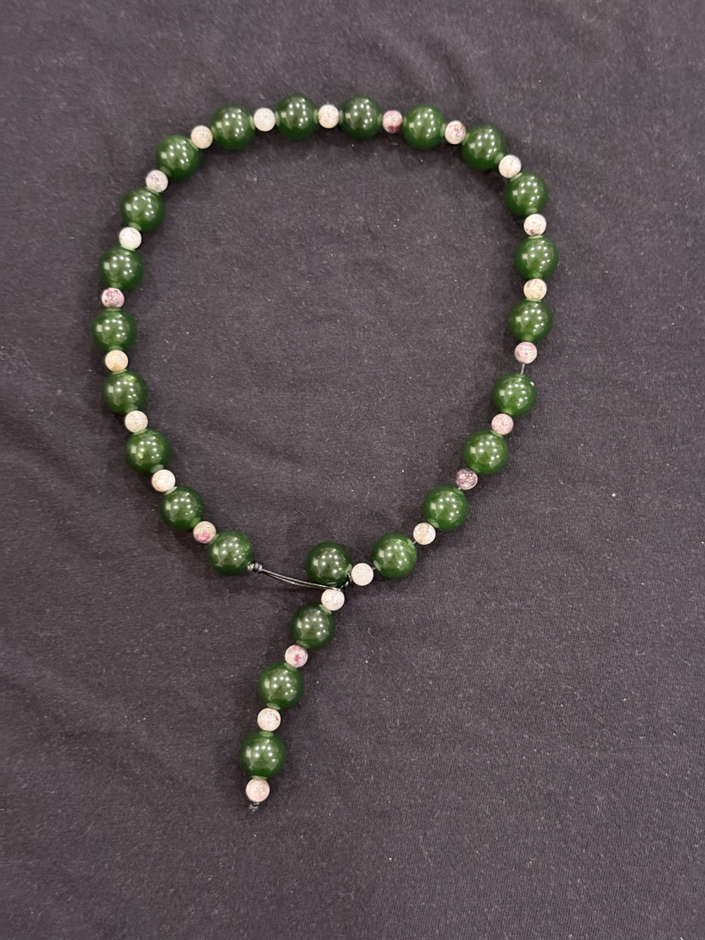 Full view of green jade and tourmaline waterfall necklace with exposed leather cord detail